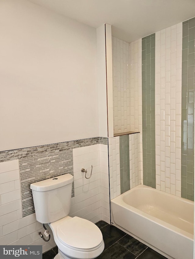 full bathroom with bathing tub / shower combination, tile patterned flooring, a wainscoted wall, toilet, and tile walls