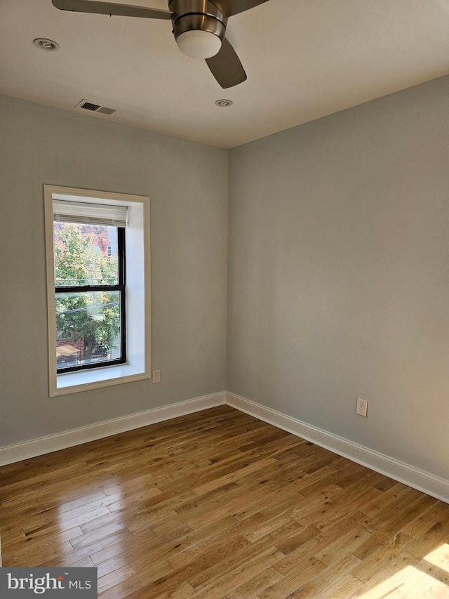 unfurnished room featuring wood-type flooring, baseboards, a ceiling fan, and visible vents