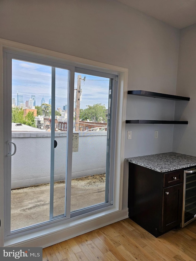 doorway to outside featuring wine cooler, light wood finished floors, and a view of city