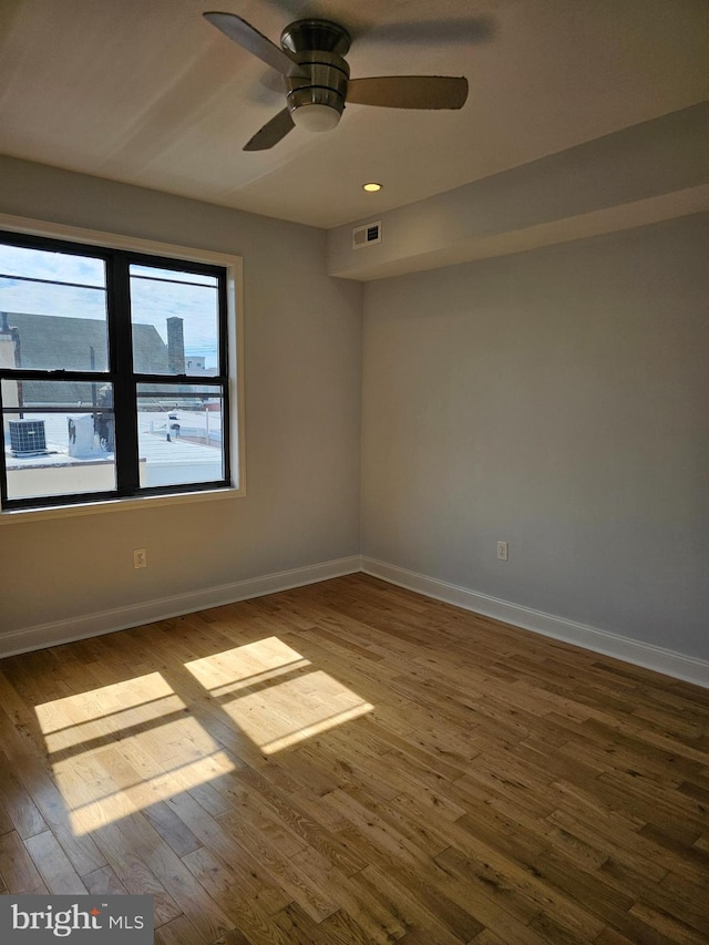 empty room with visible vents, baseboards, a ceiling fan, and wood finished floors
