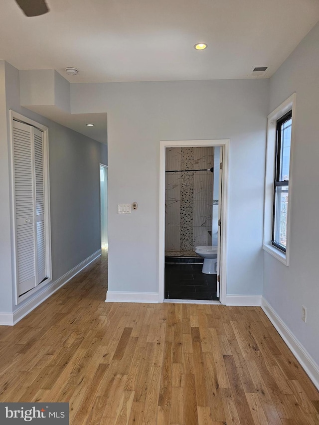 unfurnished bedroom featuring baseboards, recessed lighting, ensuite bathroom, visible vents, and wood finished floors