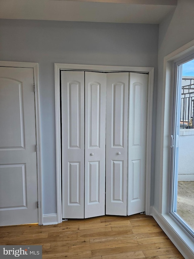 interior space featuring a closet, baseboards, and light wood-style floors