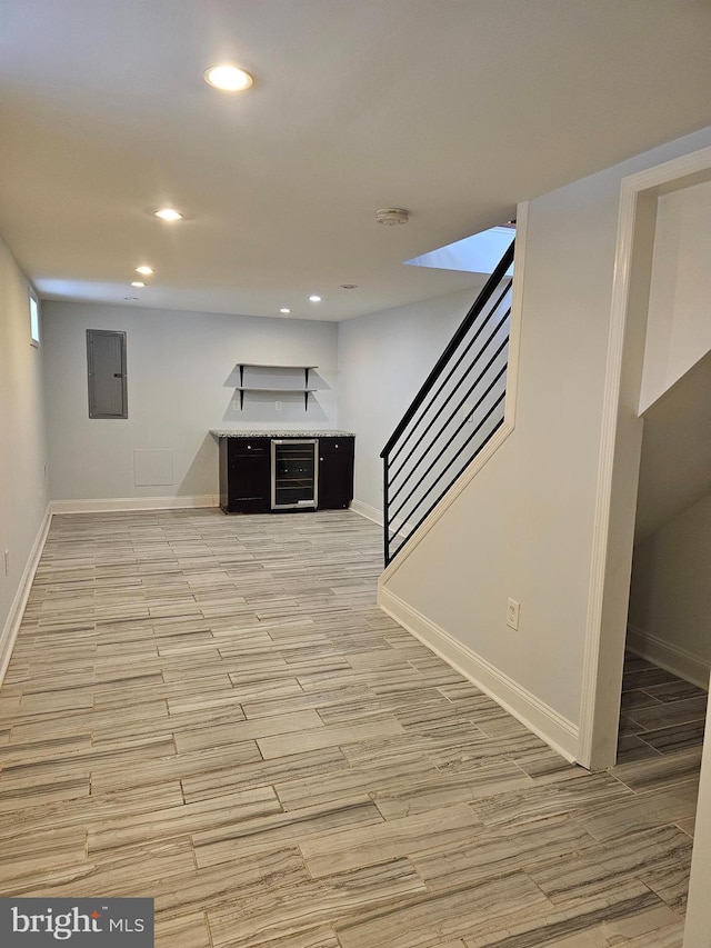 finished below grade area featuring baseboards, light wood-type flooring, wine cooler, recessed lighting, and stairs