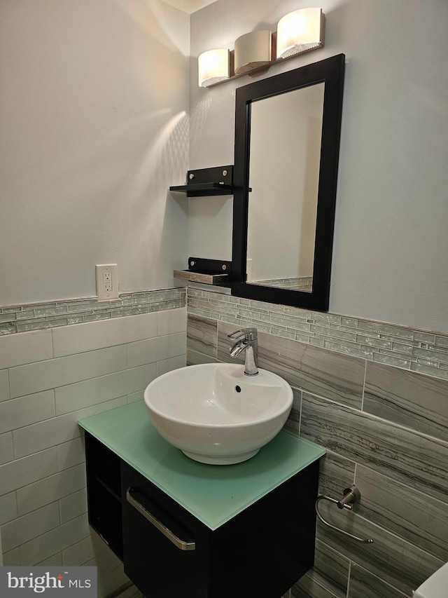 bathroom with vanity, a wainscoted wall, and tile walls