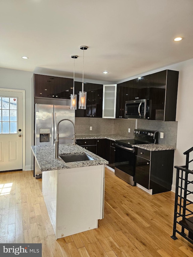 kitchen with tasteful backsplash, light wood finished floors, a sink, and stainless steel appliances