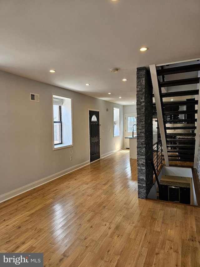 living room featuring a wealth of natural light, stairs, light wood finished floors, and visible vents