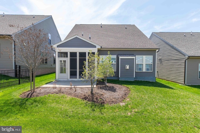 back of house with fence, a shingled roof, a patio area, a lawn, and a sunroom