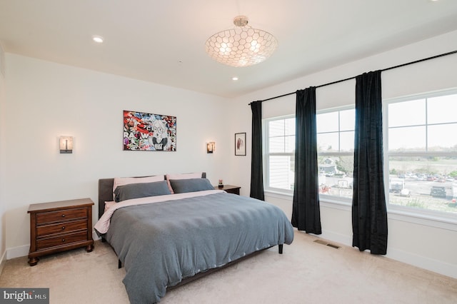 bedroom featuring light carpet, visible vents, multiple windows, and baseboards