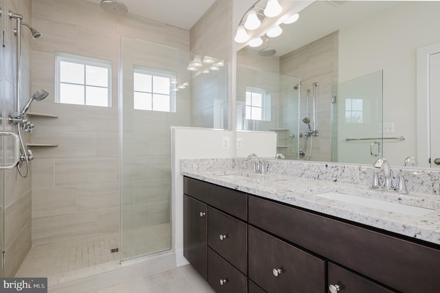 full bathroom with a shower stall, double vanity, and a sink