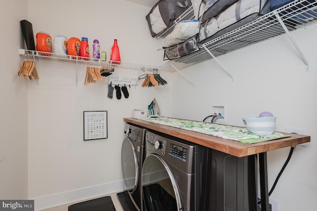 clothes washing area with baseboards, separate washer and dryer, and laundry area
