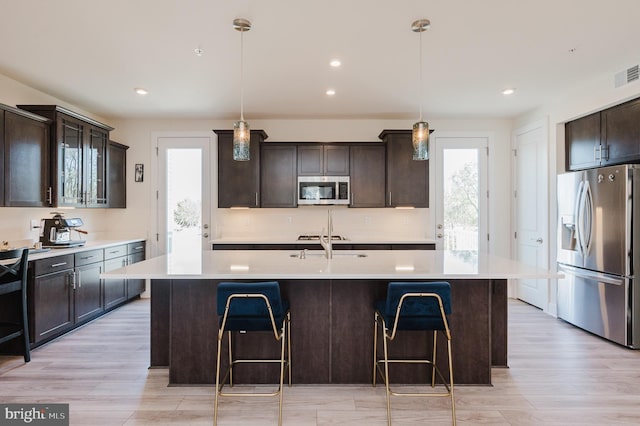 kitchen featuring light countertops, a breakfast bar area, appliances with stainless steel finishes, and dark brown cabinets