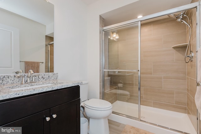 full bath featuring toilet, a stall shower, and vanity