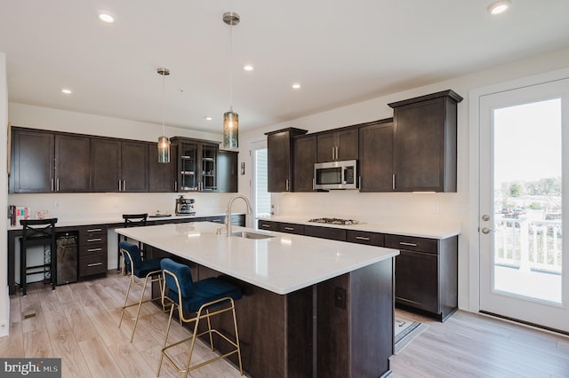 kitchen with a sink, stainless steel microwave, a breakfast bar, and a wealth of natural light