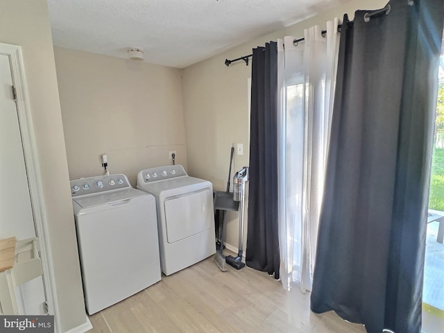 laundry area with light wood-style flooring, a textured ceiling, washer and dryer, and laundry area