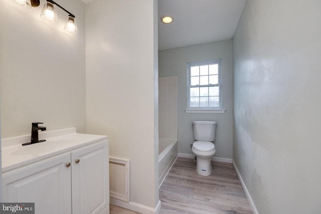 bathroom featuring toilet, wood finished floors, vanity, and baseboards
