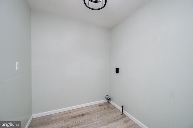 washroom with baseboards, light wood-type flooring, and laundry area