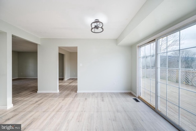 empty room with visible vents, baseboards, and light wood-type flooring