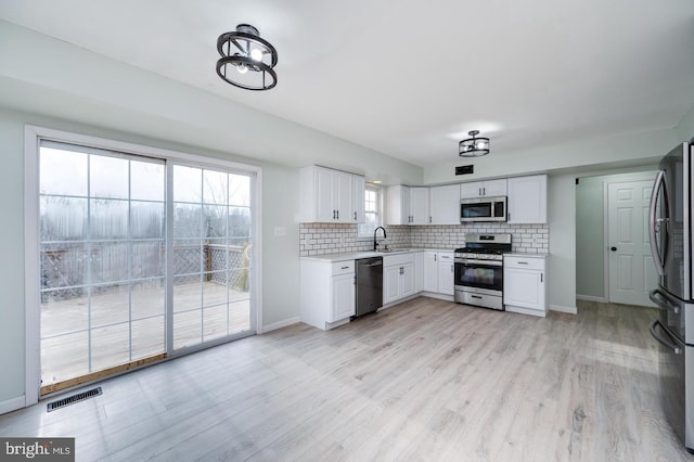 kitchen with a sink, visible vents, decorative backsplash, and stainless steel appliances