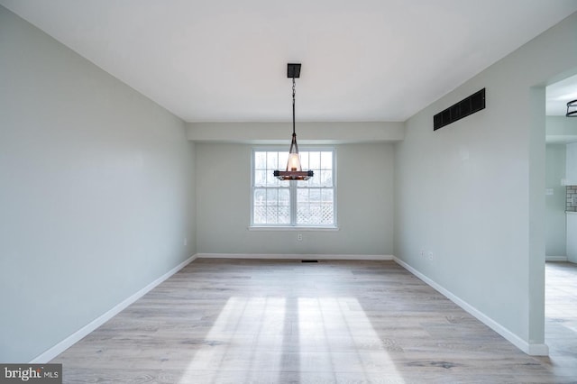 unfurnished dining area featuring a chandelier, light wood-type flooring, baseboards, and visible vents