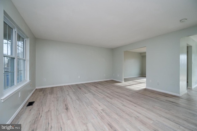 empty room with light wood-style floors, baseboards, and visible vents