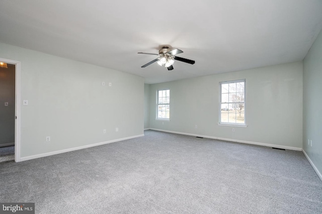 carpeted spare room featuring visible vents, baseboards, and ceiling fan