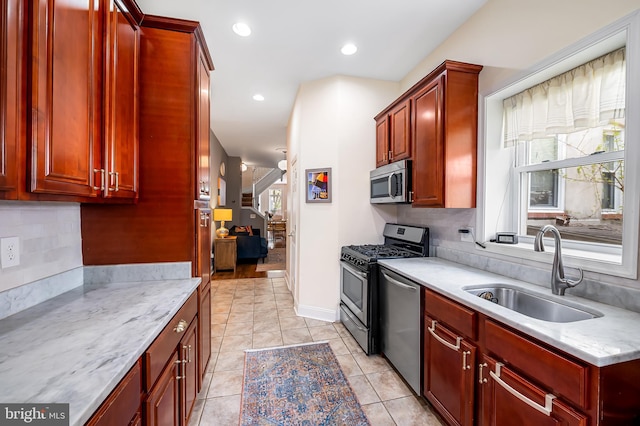 kitchen with a sink, appliances with stainless steel finishes, reddish brown cabinets, healthy amount of natural light, and recessed lighting