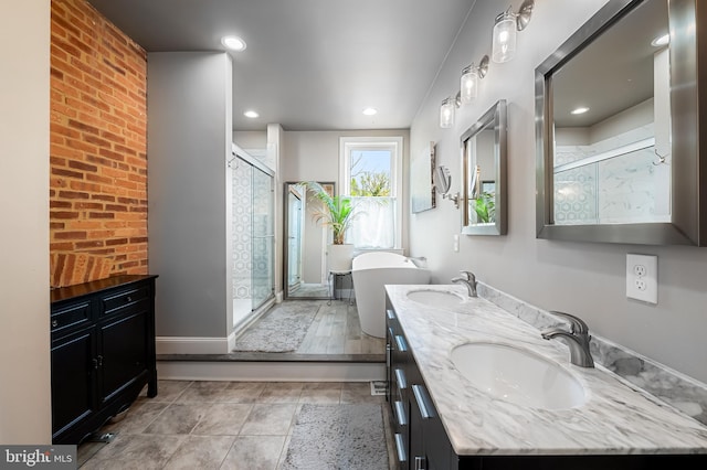 bathroom featuring a stall shower, a freestanding bath, double vanity, recessed lighting, and brick wall