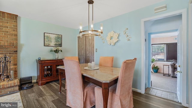 dining room featuring visible vents, baseboards, an inviting chandelier, and wood finished floors