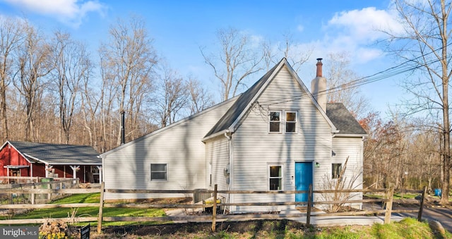 back of property with fence private yard and a chimney