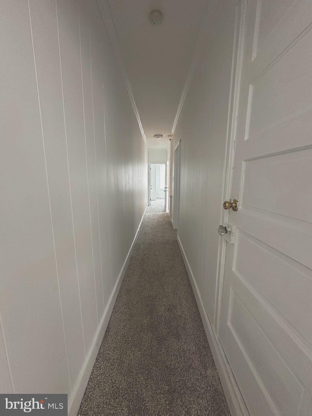 corridor featuring baseboards, ornamental molding, and carpet