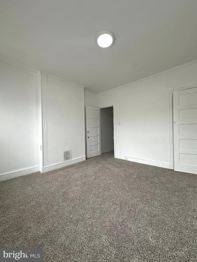 carpeted spare room featuring ornamental molding, baseboards, and visible vents