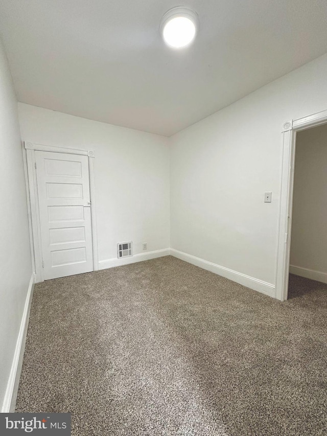 carpeted empty room featuring visible vents and baseboards