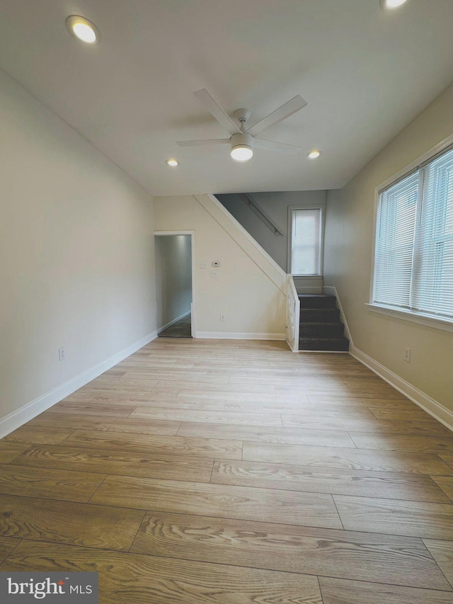 unfurnished living room featuring baseboards, ceiling fan, light wood finished floors, recessed lighting, and stairs