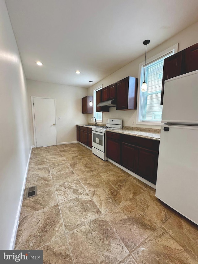 kitchen featuring visible vents, baseboards, a sink, white appliances, and dark brown cabinetry