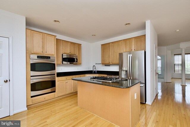 kitchen featuring a sink, light wood finished floors, a center island, stainless steel appliances, and ornate columns