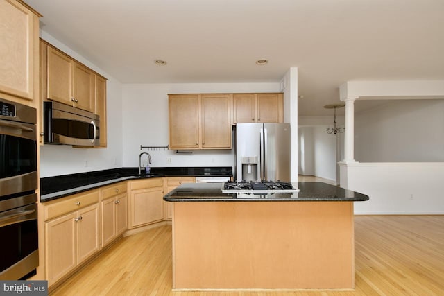 kitchen featuring a kitchen island, light wood-style floors, dark stone counters, light brown cabinets, and stainless steel appliances