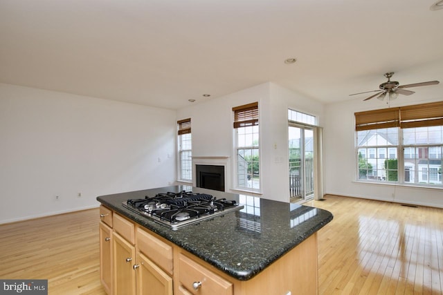kitchen featuring open floor plan, light wood-style flooring, a wealth of natural light, and stainless steel gas stovetop