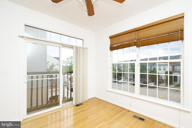 empty room featuring baseboards, a ceiling fan, wood finished floors, and visible vents