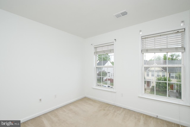 spare room with baseboards, visible vents, and light carpet