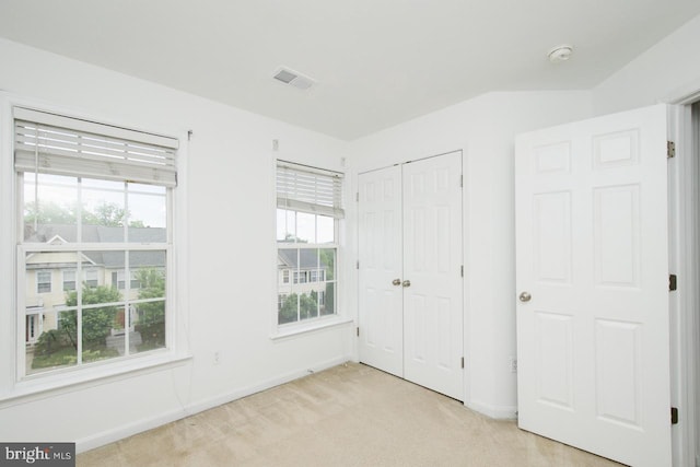 unfurnished bedroom with baseboards, visible vents, light carpet, and a closet