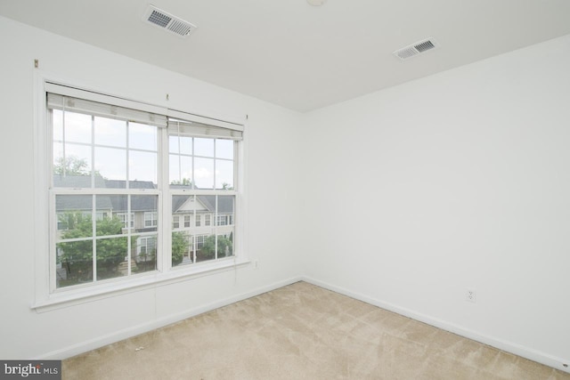empty room with light colored carpet, baseboards, and visible vents