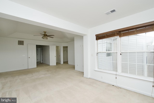 unfurnished room with light colored carpet, a ceiling fan, visible vents, and baseboards