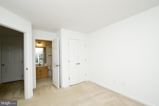unfurnished bedroom with baseboards, light colored carpet, and a closet