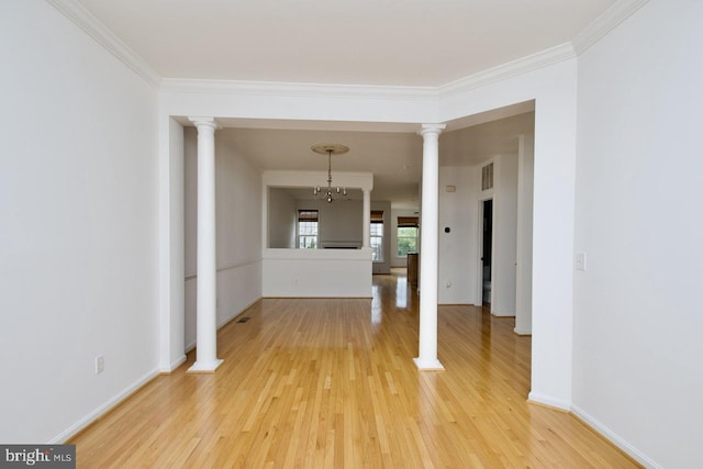 unfurnished dining area featuring baseboards, light wood-style flooring, decorative columns, and ornamental molding