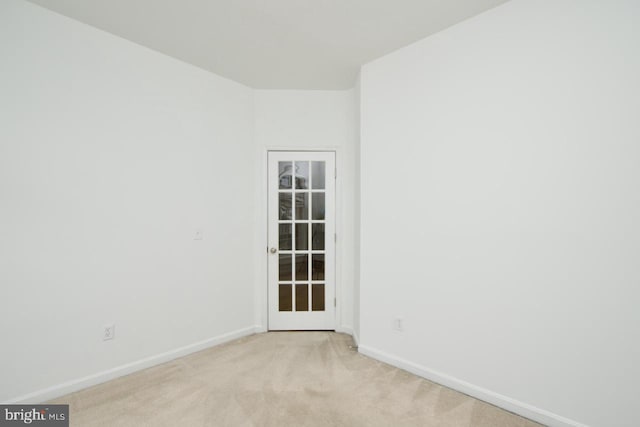 unfurnished room featuring baseboards and light colored carpet