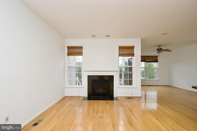 unfurnished living room with baseboards, visible vents, a fireplace with flush hearth, and hardwood / wood-style flooring
