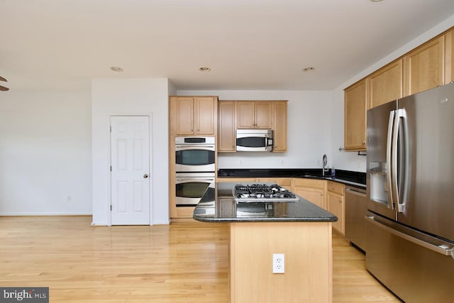 kitchen with light wood-style floors, a sink, a kitchen island, and stainless steel appliances