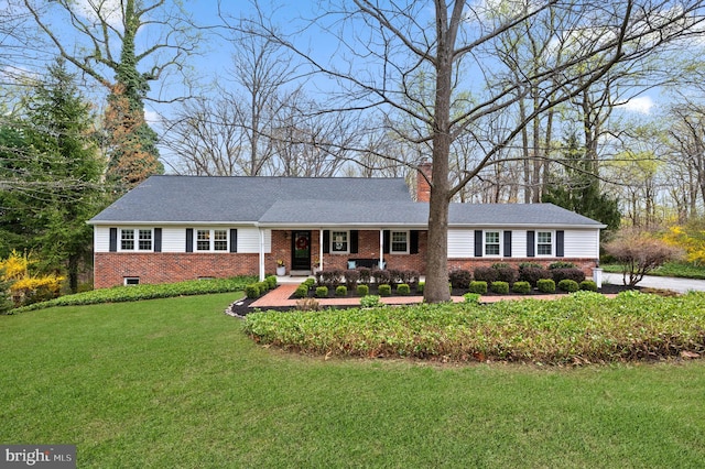 single story home featuring a chimney, covered porch, a front yard, and brick siding