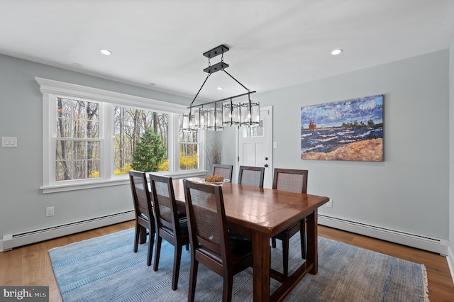 dining room with wood finished floors, a chandelier, and a baseboard heating unit