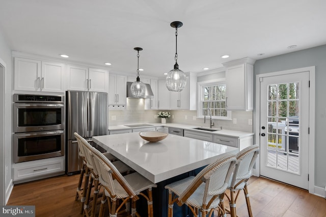kitchen with a breakfast bar area, a sink, stainless steel appliances, and light countertops